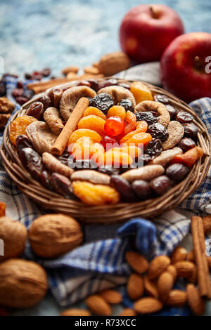 Zusammensetzung von getrockneten Früchten und Nüssen in kleinen Wicker Schüssel auf steinernen Tisch platziert Stockfoto