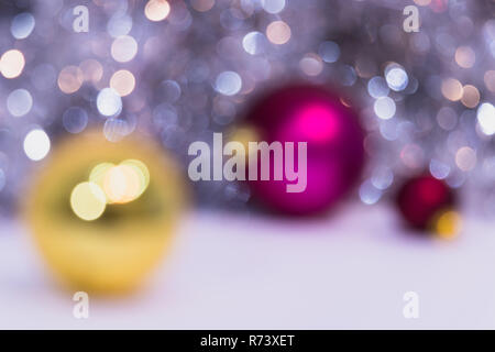 Blurry Christmas background mit Weihnachtskugeln und Bokeh. Drei XMAS Kugeln Gold und Pink. Neues Jahr Feier Stockfoto
