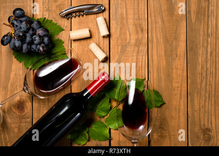 Komposition mit Flasche und Glas Wein und Traubenmost Bündel und Weinblätter auf Holz- Hintergrund. Ansicht von oben mit der Kopie. Stockfoto