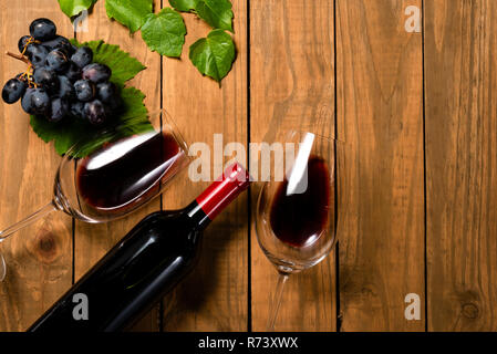 Komposition mit Flasche und Glas Wein und Traubenmost Bündel und Weinblätter auf Holz- Hintergrund. Ansicht von oben mit der Kopie. Stockfoto