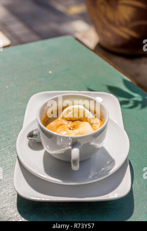 Affogato Kaffee in weißen Schale am grünen Tisch im Freien. Stockfoto