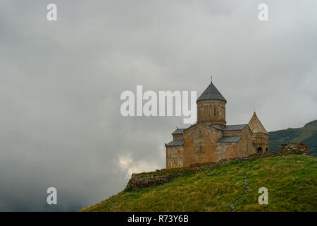 Die gergeti Trinity Kirche hoch auf den Hügeln mit Blick auf das Dorf von Gergeti, Georgia. Name der Orthodoxen Kirche ist die Kirche der Heiligen Dreifaltigkeit Stockfoto