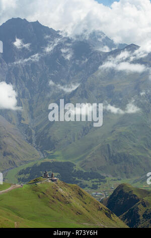 Die gergeti Trinity Kirche hoch auf den Hügeln mit Blick auf das Dorf von Gergeti, Georgia. Name der Orthodoxen Kirche ist die Kirche der Heiligen Dreifaltigkeit Stockfoto