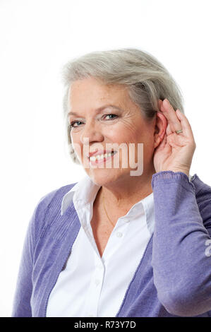 Reife Frau mit Hand zum Ohr Stockfoto