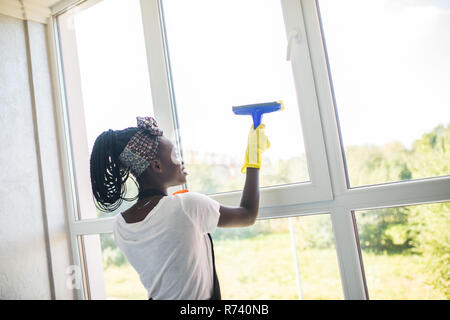 Afrikanische Frau reinigen Glas mit Gummi Glasreiniger Stockfoto