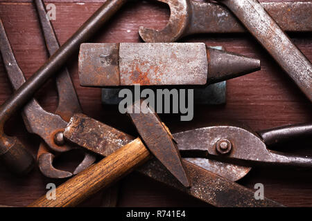 Alten rostigen robuste Amboss und andere Schmied Werkzeuge auf Braun Natur Holz- Hintergrund. Flach Ansicht von oben. Stockfoto