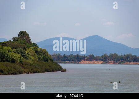 Don Daeng, Laos - 27. April 2018: Fischerboot Navigieren auf dem Mekong durch grüne Wälder und Berge umgeben Stockfoto