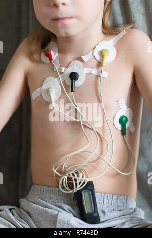 Kind auf dem Sofa sitzen. Herz Elektrokardiogramm oder Überwachung der Herzfunktion mit Holter. Stockfoto