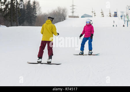 Junges Paar Snowboarder schieben Sie den Hang hinunter in einem Wintertag. Glückliches Paar Athleten. Stockfoto