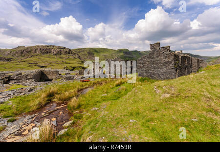 Verlassene und verfallene Schieferabbau Gebäude stehen inmitten von Geröll Tipps und die moelwyn Berge im Tal über Cwmorthin Blaenau Ffestiniog in Sn Stockfoto