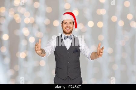 Glückliche Menschen in santa hut Holding etwas Imaginäres Stockfoto