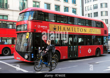 Rote Doppeldecker Bus mit Werbung auf der Seite für den amerikanischen West End Theater spielen Hamilton und Radfahrer warten auf Fahrräder in London UK KATHY DEWITT Stockfoto