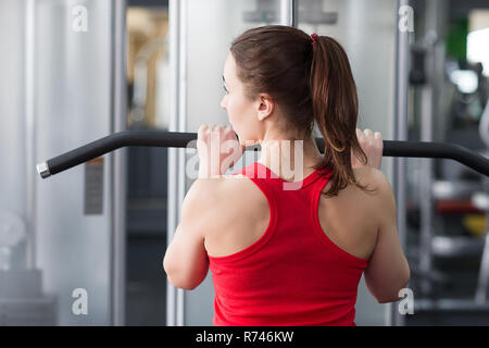 Junge sportliche Frau engagiert in der Turnhalle. Die Muskeln am Körper eines schönen jungen Mädchens. Stockfoto