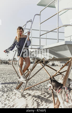 Junge Frau mit Haustier Hunde von lifeguard Tower Stockfoto