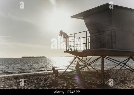 Frau auf lifeguard Tower, Sonnenuntergang im Hintergrund Stockfoto