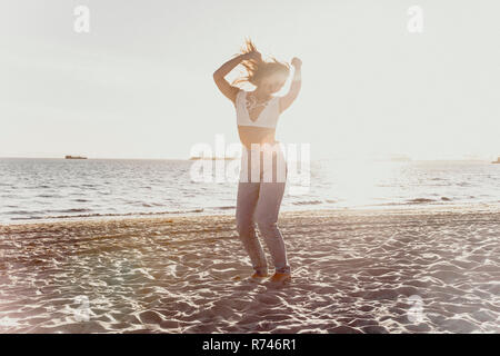Junge Frau am Strand tanzen Stockfoto
