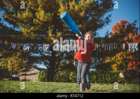 Mädchen schwingen Baseballschläger im Garten Stockfoto