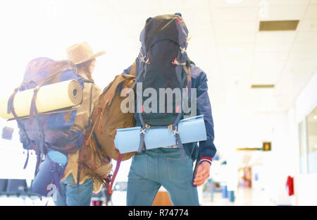 Junges Paar am Flughafen, Rucksäcke, Rückansicht Stockfoto