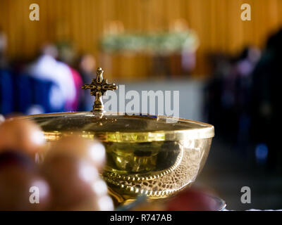 Golden copon mit einem Kreuz als Angebot vor katholische Messe unscharfen Hintergrund und Trauben im Vordergrund Stockfoto