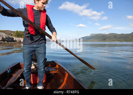 Reifen Mann stehen Ruder im Ruderboot, Aure, Mehr og Romsdal, Norwegen zu verwenden Stockfoto