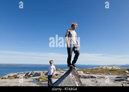 Junge und Vater mit Blick von der Oberseite der Felsformation über Landschaft, Aure, Mehr og Romsdal, Norwegen Stockfoto