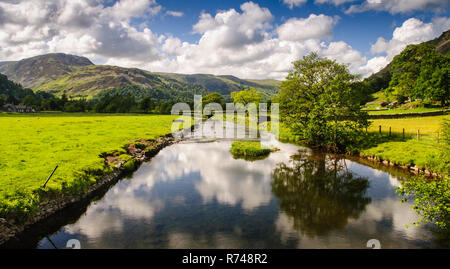 Goldrill Beck Fluss fließt durch Felder Felder in das ullswater Tal des englischen Lake District, mit Glenridding Dodd Berg hinter. Stockfoto