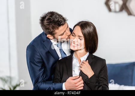 Schöner Freund küssen Lächeln attraktive Freundin, bevor Arbeiten zu Hause Stockfoto