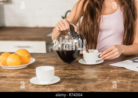 7/8 Bild der Frau gießen Kaffee in die Tasse in Morgen in der Küche Stockfoto