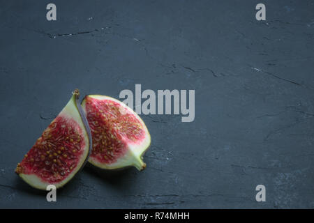 Frische Feigen in Scheiben schneiden. Abb. closeup auf schwarzen Beton. Platz für Text. Ernährung frisches Obst. Stockfoto