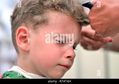 Junge bekommt seine Haare schneiden bei Long curly Der Friseur Haar Stockfoto