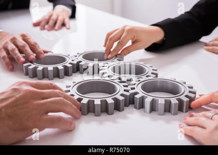 Geschäftsleute verbinden Zahnräder auf Schreibtisch Stockfoto