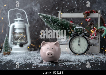 Bild von piggy Bank, Weihnachtsdekoration von Kegeln und Beeren, Holzkiste, rote Kerzen, Schnee Stockfoto