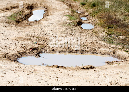 Wasser gefüllten Spurrillen im Schlamm, der aussieht wie ein Smiley. Stockfoto