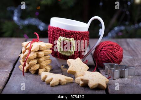 Weihnachten - aus Gewirken aus Wolle Tassen und sternförmigen Lebkuchen auf einem Holztisch Stockfoto