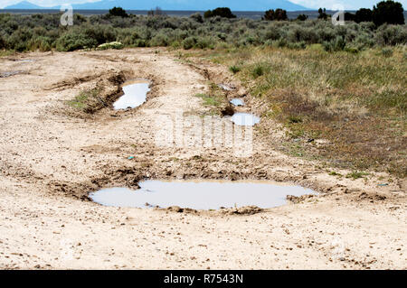 Wasser gefüllten Spurrillen im Schlamm, der aussieht wie ein Smiley. Stockfoto