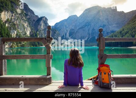 Mädchen Backpacker sitzen auf einem Pier und Pragser See Stockfoto