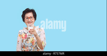 Ältere Frau mit einem Glas Milch, auf weißem Hintergrund. Stockfoto