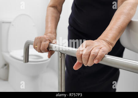 Ältere Frau Holding auf Handlauf in der Toilette. Stockfoto