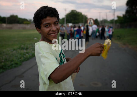 Managua, Nicaragua. 07 Dez, 2018. Eine obdachlose junge spielt eine 'Maraca' während einer Prozession in der Kathedrale von Managua während der religiösen Feier 'La Gritería'. Die Menschen auf der Straße schreien zu Ehren der Jungfrau Maria. Im Vergleich zu den vergangenen Jahren nur wenige Menschen auf die Straße gingen, während dieser Feier. Credit: Carlos Herrera/dpa/Alamy leben Nachrichten Stockfoto