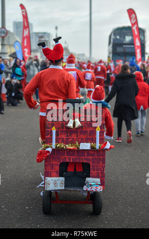 Brighton, Sussex, UK. 08. Dezember 2018. Die Kinder rennen in der jährlichen Brighton Santa Strich entlang der Küste von Hove, Geld für die lokale Rockinghorse Nächstenliebe. Rockinghorse ist ein Brighton-basierte Nächstenliebe, unterstützt Kinder in Sussex seit über 50 Jahren. Foto: Simon Dack/Alamy leben Nachrichten Stockfoto