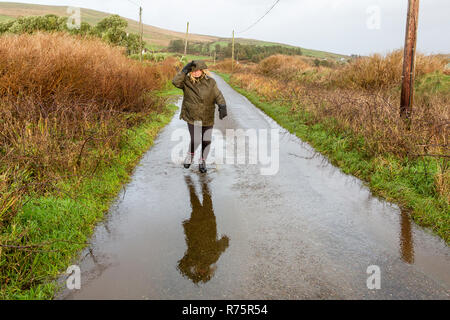 Frau Spritzen in Pfütze bei starkem Wind auf Grafschaft Lane im County Kerry Irland Stockfoto