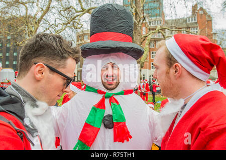 London, UK, 8. Dezember 2018. Santas Halt im Park vor der Euston Station für eine Atempause und einige mehr zu trinken. Santacon, eine gemeinnützige, nicht-politische, nicht-religiösen, Christmas Parade durch London. Teilnehmer dress up in Santa Anzüge und ein führender Santa von verschiedene Ansatzpunkte in Trafalgar Square. Credit: Guy Bell/Alamy leben Nachrichten Stockfoto