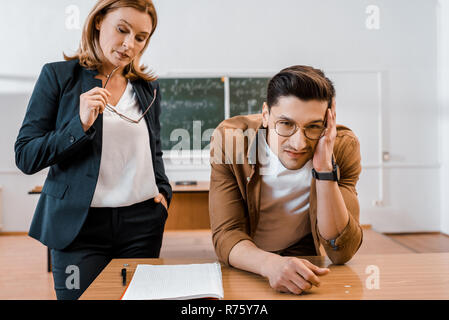 Unzufrieden Lehrerin und männliche Kursteilnehmer während der Untersuchung im Klassenzimmer Stockfoto