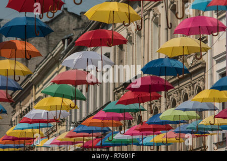 Bunte Sonnenschirme hängen auf dem Hintergrund der alten Stadt Lemberg Stockfoto