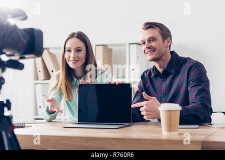 Lächelnd video Blogger Aufnahme vlog und zeigen auf Laptop mit leerer Bildschirm im Büro Stockfoto