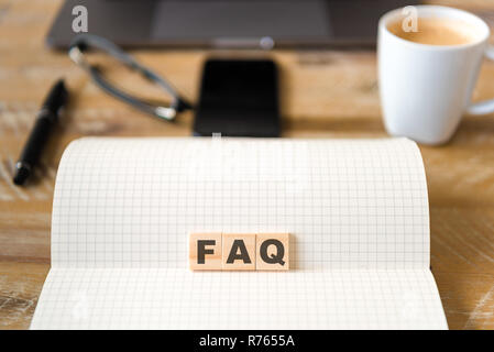 Nahaufnahme auf das Notebook um Holz Tisch Hintergrund, auf Holzblöcken mit Buchstaben machen FAQ Text konzentrieren Stockfoto