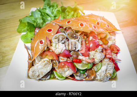 Seafood Platte auf Holztisch/Seafood Buffet gemischter Salat würzig mit Garnelen cockle Krabben und Salat Salat Gemüse auf weiße Platte - Meeresfrüchte Thai Stil Stockfoto