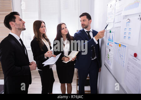 Geschäftsleute in Diagrammen auf dem Whiteboard befestigt auf der Suche Stockfoto
