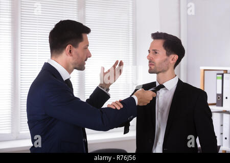 Wütend Geschäftsmann Holding seines Partners Binden Stockfoto