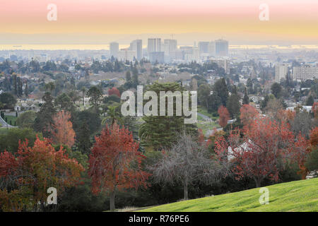 Blick auf den Sonnenuntergang von Oakland Downtown und die Bucht von San Francisco von einem Hügel in Mountain View Friedhof. Stockfoto